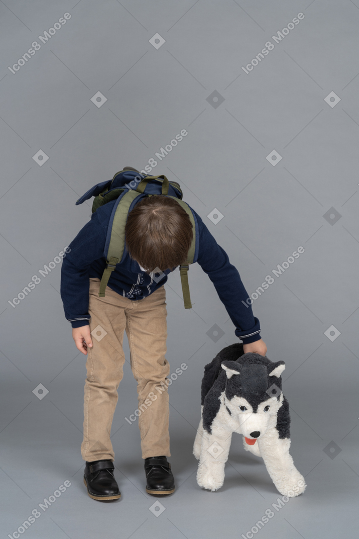 Schoolboy playing with a plush toy