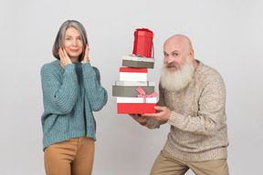 Hombre de edad dando regalos a una mujer madura elegante