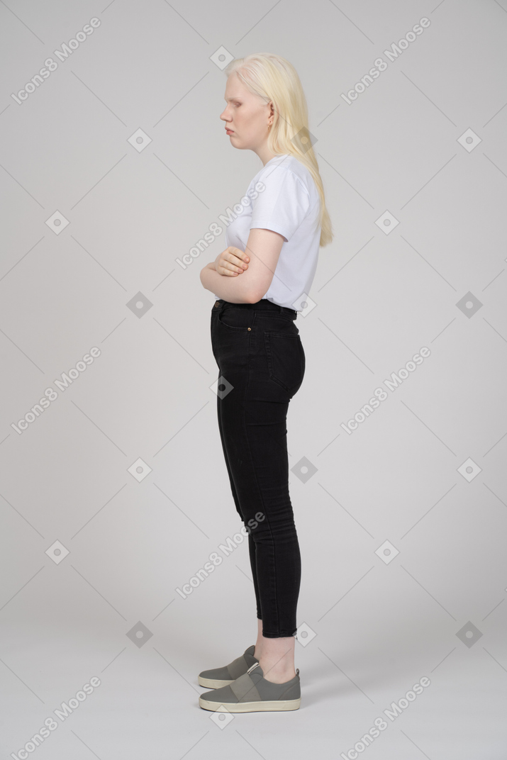 一名年轻女子双臂交叉站立的侧视图