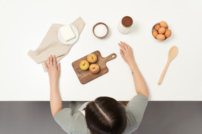 A female baker sitting at the table with baking stuff