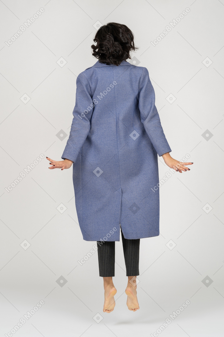 Back view of woman in coat mid-air