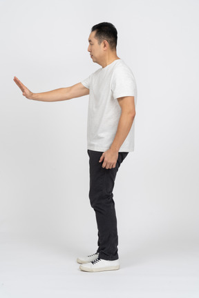 Вид сбоку человека в повседневной одежде, показывающего жест стоп