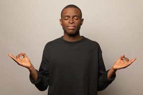 Молодой человек в позе медитации с закрытыми глазами