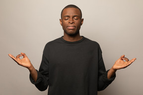 Jeune homme en pose de méditation avec les yeux fermés