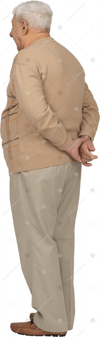 Vista laterale di un vecchio in abiti casual in piedi con le mani dietro la schiena