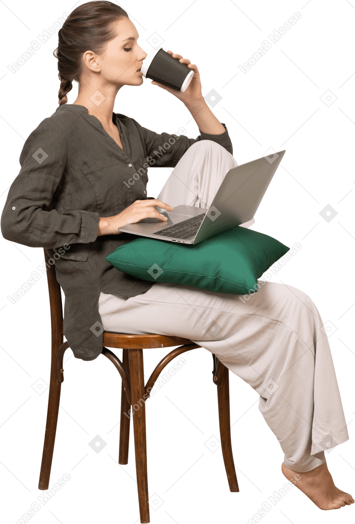 一个困惑的年轻女子坐在椅子上，拿着她的笔记本电脑和喝咖啡的侧视图