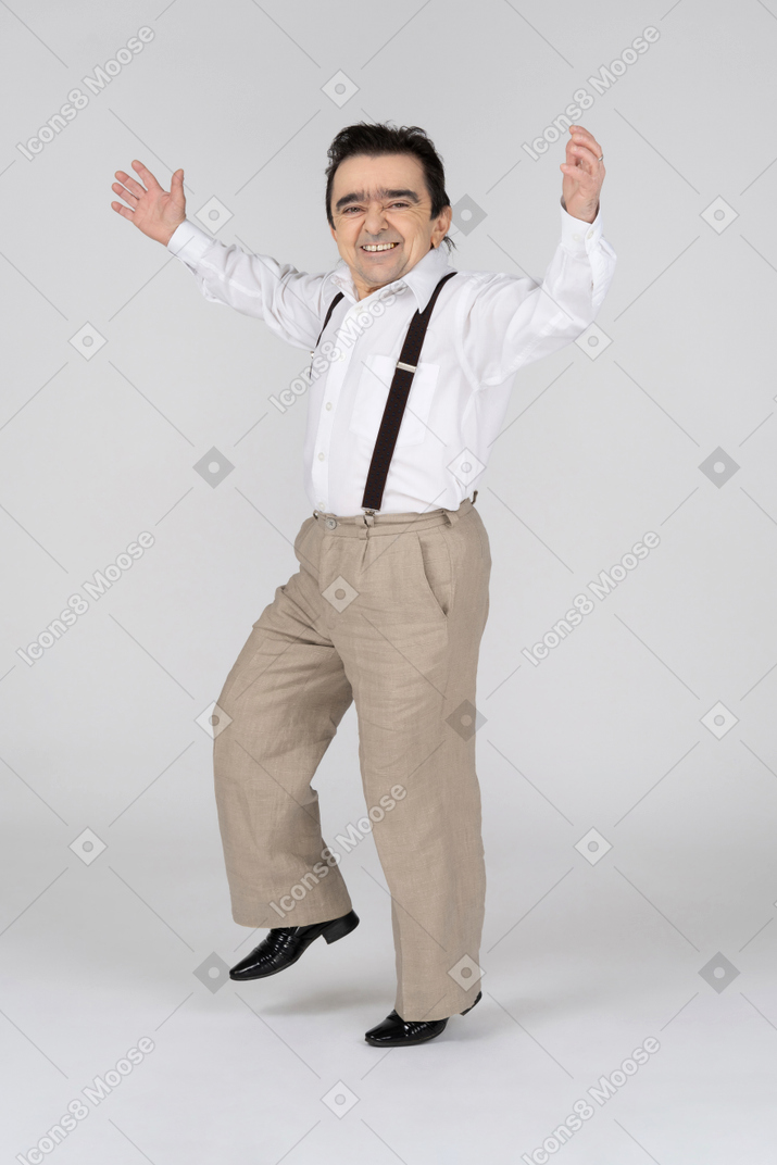 Счастливый мужчина средних лет с раскинутыми руками стоит на одной ноге
