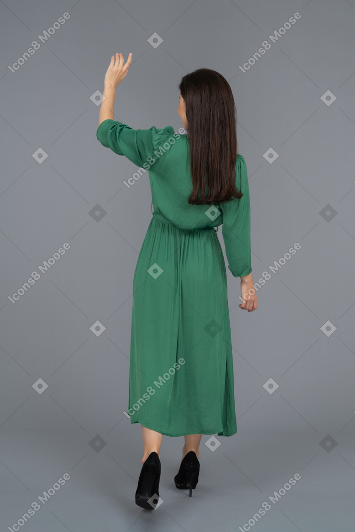 A young woman waving hand backwards to camera