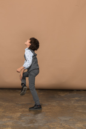 Vista lateral de um menino de terno dançando