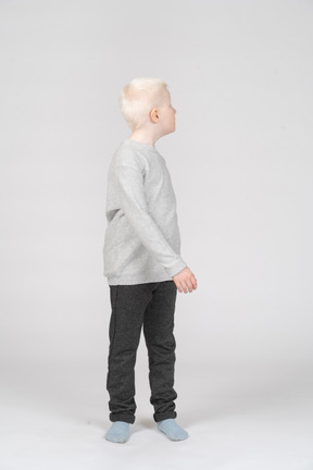 Vista frontal de un niño rubio caminando mirando hacia los lados