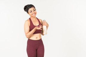 Young indian woman in sportswear holding sport bottle