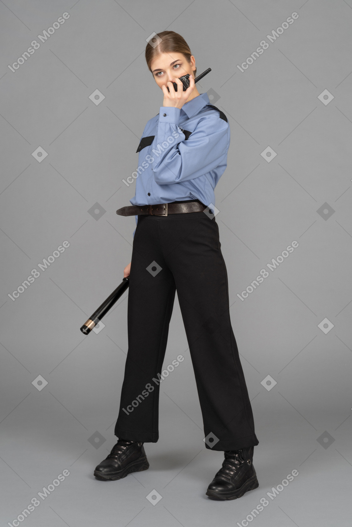 Female security guard with a baton speaking on the radio