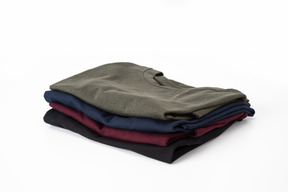 Folded dark colored t-shirts on white background