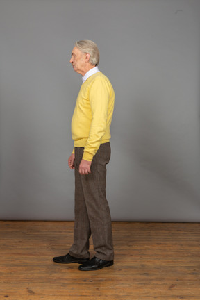 Vue latérale d'un vieil homme mécontent dans un pull jaune à côté