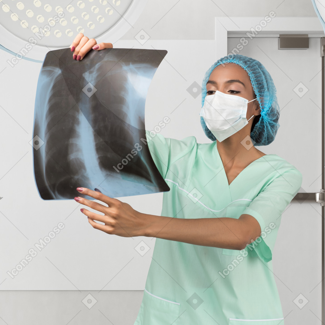 A woman wearing a surgical mask holding a x - ray