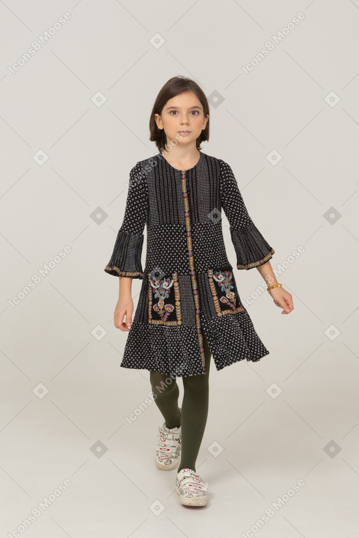 Vista frontal de uma menina andando em um vestido cinza