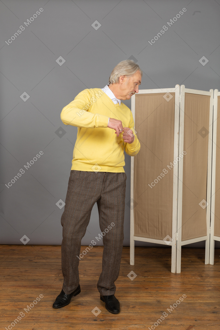 Vista frontal de um homem idoso de blusa amarela se virando