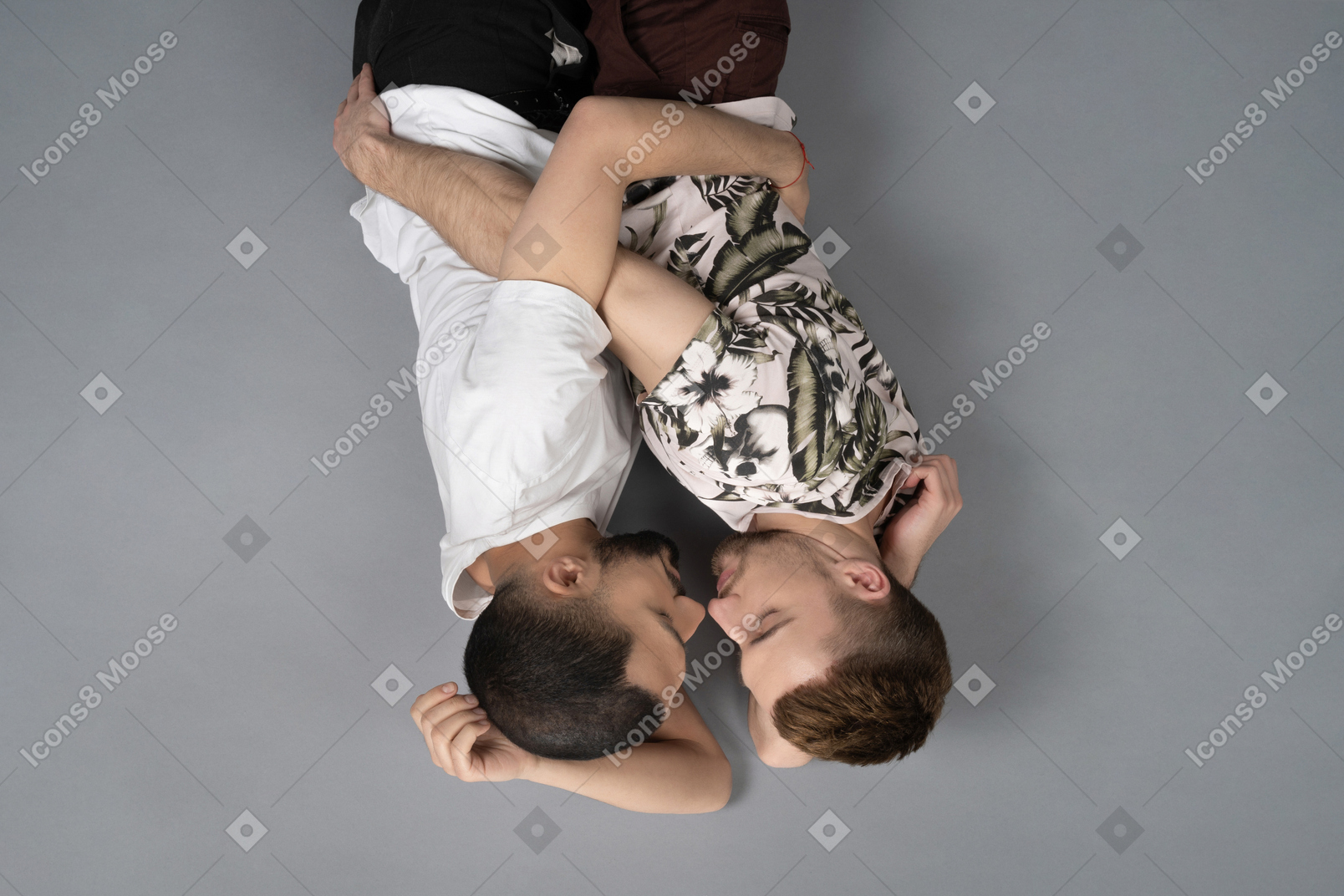 Flache lage von zwei jungen männern, die auf den seiten auf dem boden liegen und sich umarmen