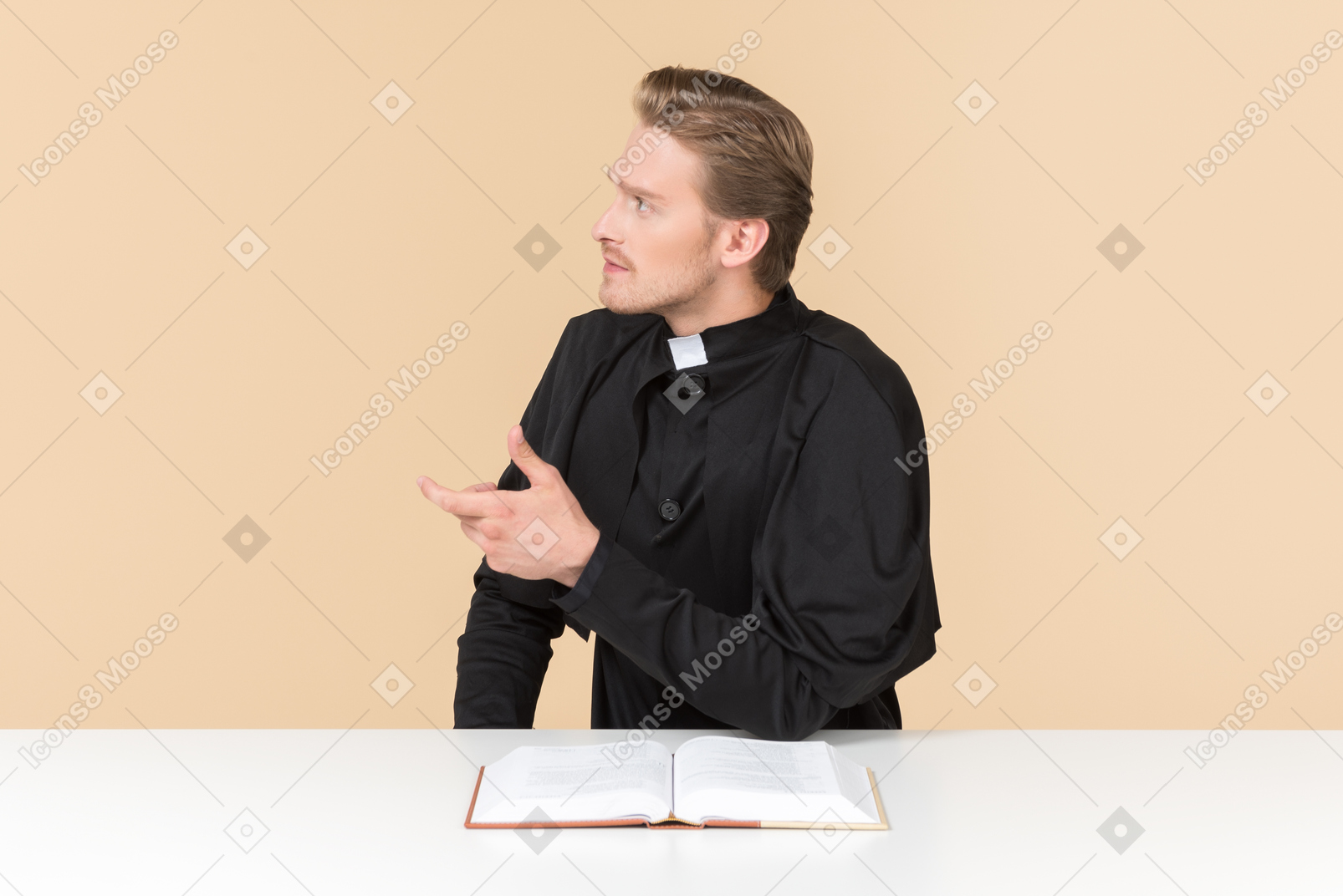 Catholic priest sitting at the table with open bible book and like saying something