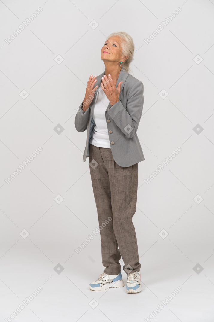 Вид сбоку счастливой старушки в костюме смотрит вверх и молится