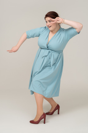 Vista lateral de uma mulher de vestido azul mostrando o sinal v