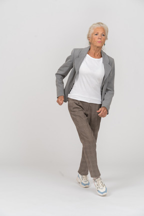 Front view of an old lady in suit jumping