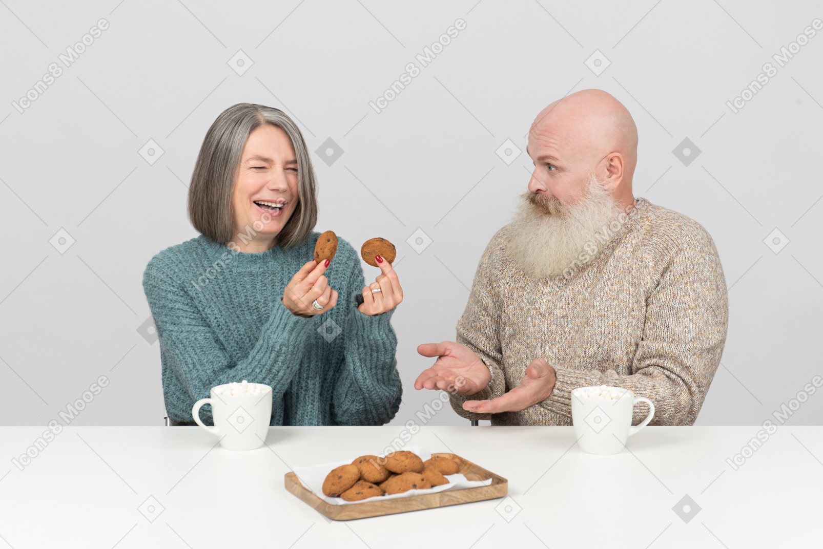 Aged woman laughing hard while holding cookies and her husband doesn't get it