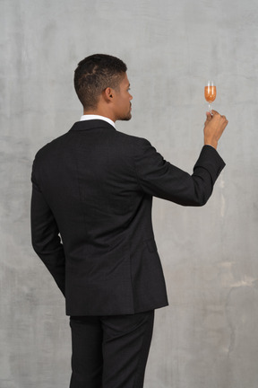 Vue arrière du jeune homme avec un verre de flûte proposant un toast