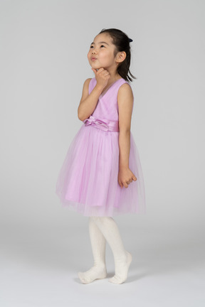 Little girl in pink dress looking away dreamily