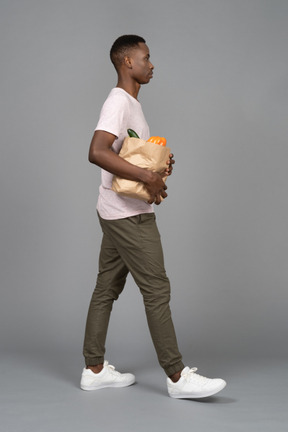 A young man carrying a grocery bag