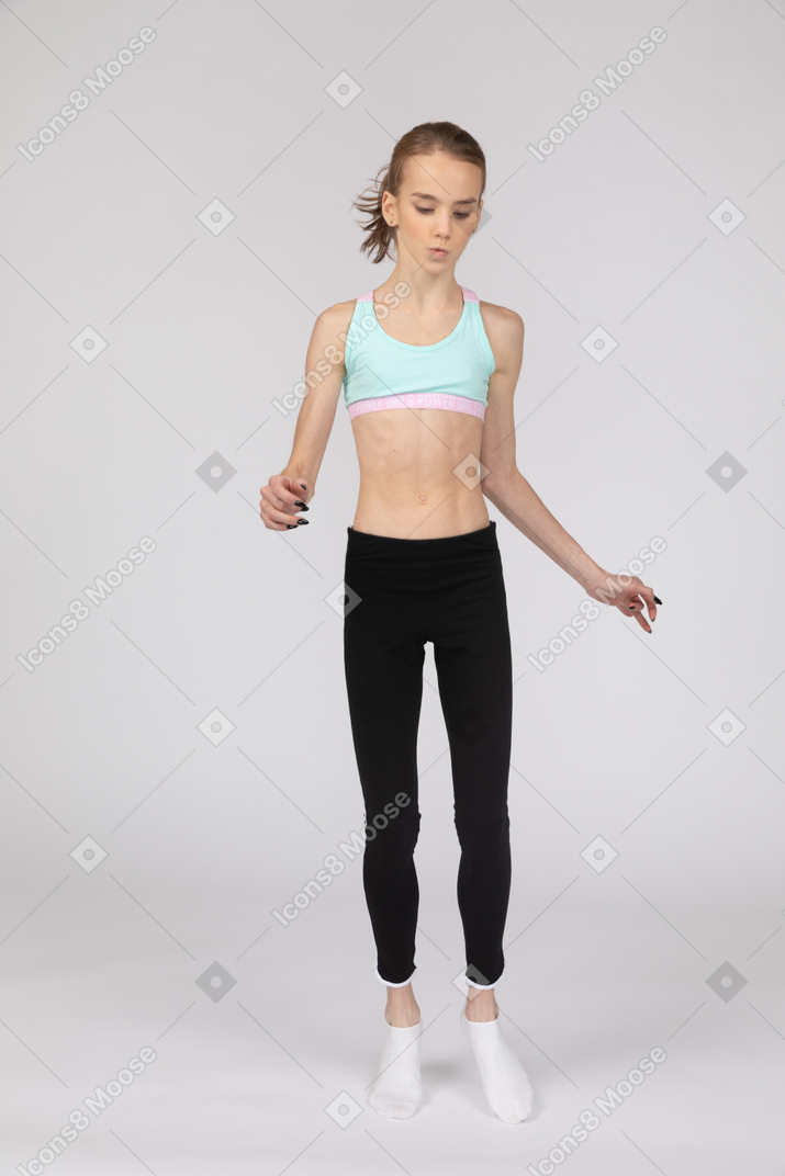 一个年轻的女孩，在运动服举起手，往下看的前视图