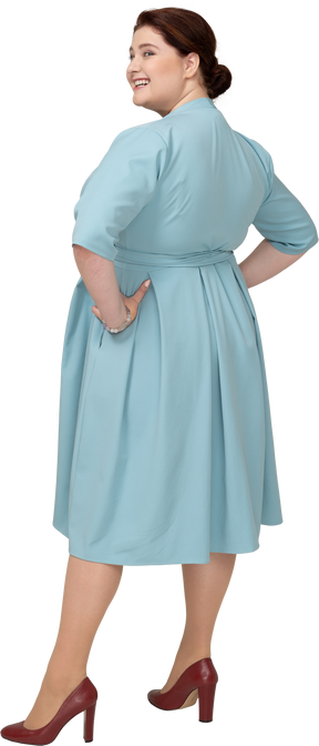 一个身着蓝色裙子、双手叉腰的女人的后视图