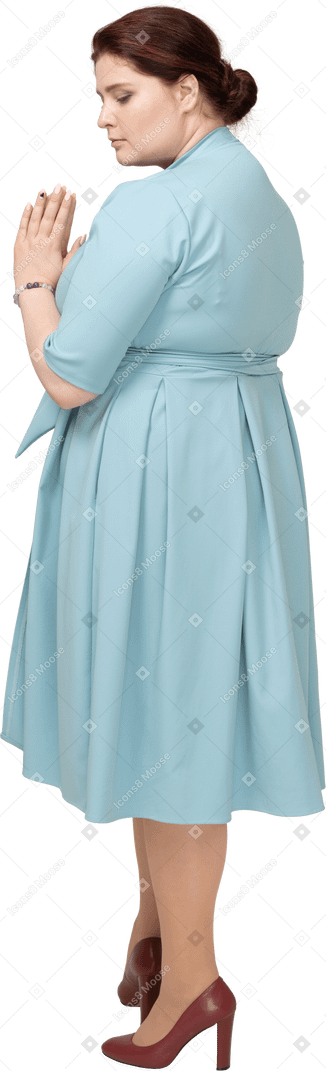 Vista lateral de una mujer en vestido azul haciendo gesto de oración