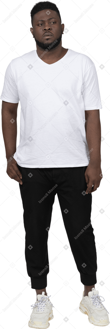 흰색 티셔츠를 입은 짙은 색의 젊은 남자가 가만히 서 있는 모습
