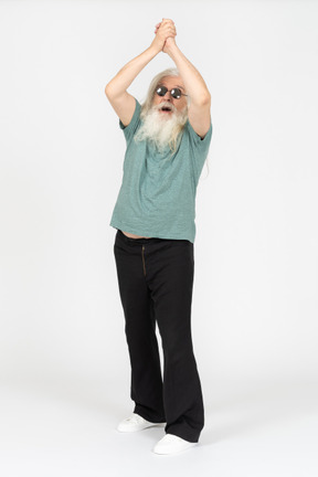 Vue de trois quarts du vieil homme à lunettes de soleil tenant la main au-dessus de la tête