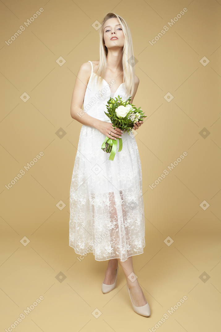 Braut, die hochzeitsblumenstrauß hält und für ein bild aufwirft