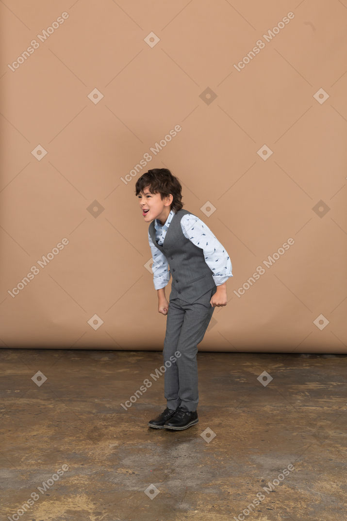 Angry boy in suit standing with clenched fists