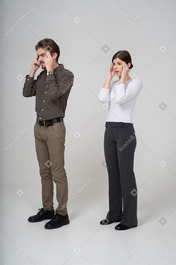 Three-quarter view of a shocked young couple in office clothing touching head