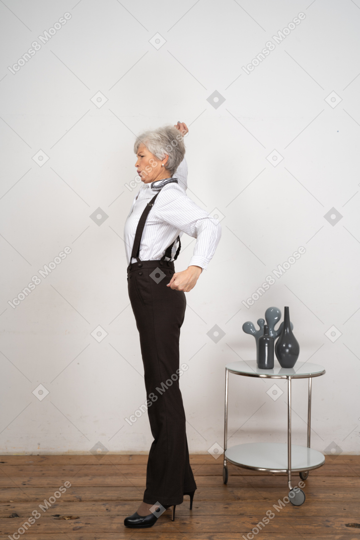 Side view of an old lady in office clothing stretching her hands