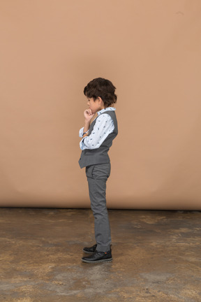 Vista lateral de un chico lindo pensativo en traje