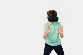 Niño con casco de realidad virtual tocando una pared invisible