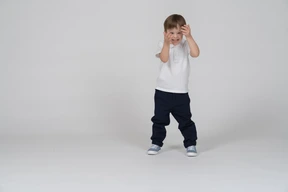 Smiling shy boy standing and covering his face