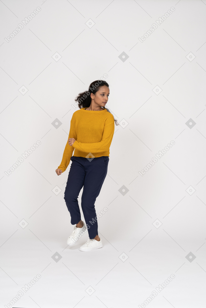 Vista frontal de uma garota com roupas casuais correndo para a frente