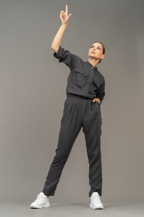 Front view of a young woman in a jumpsuit outstretching her arm