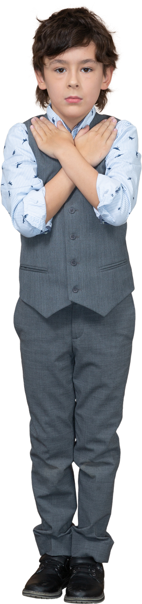 Vista frontal de un niño con traje gris de pie con las manos en los hombros