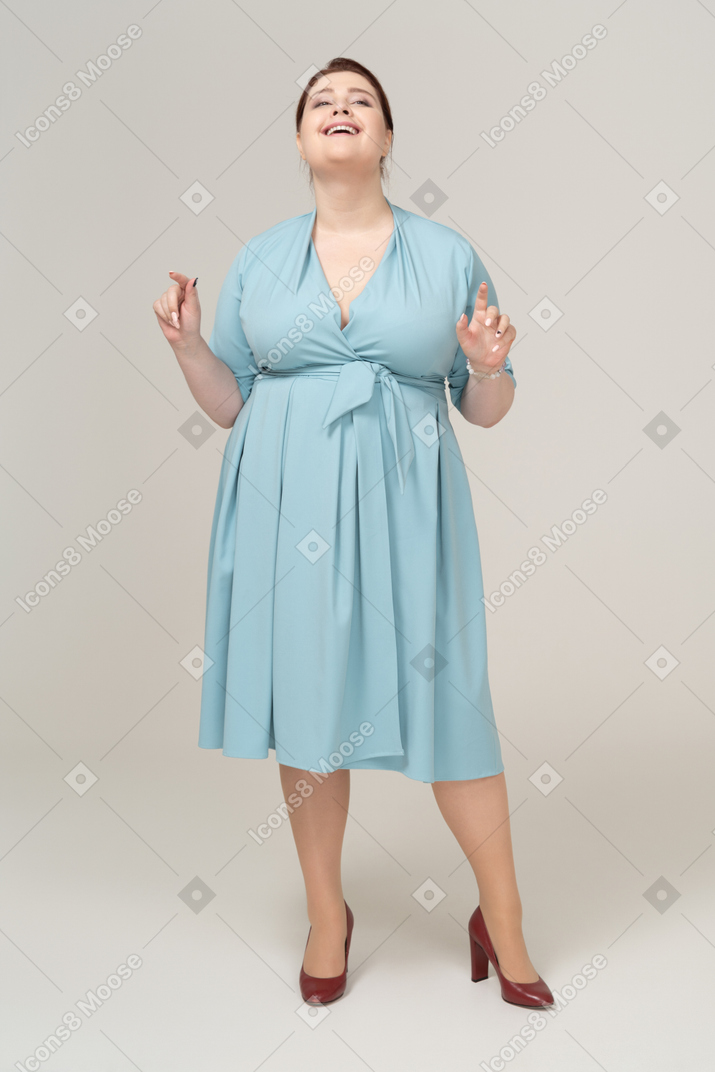 一个快乐的女人在蓝色连衣裙打手势的前视图