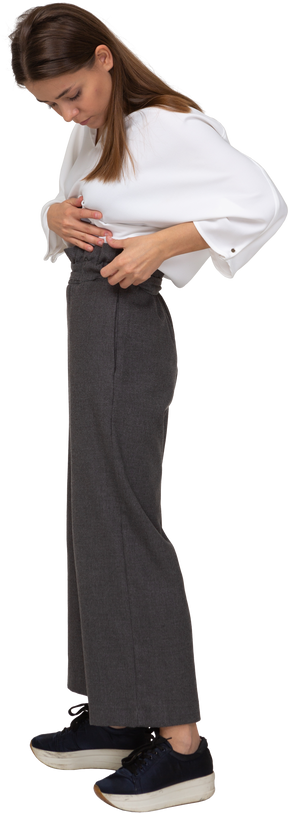 Vista frontal de uma jovem com roupa de escritório ajustando as calças