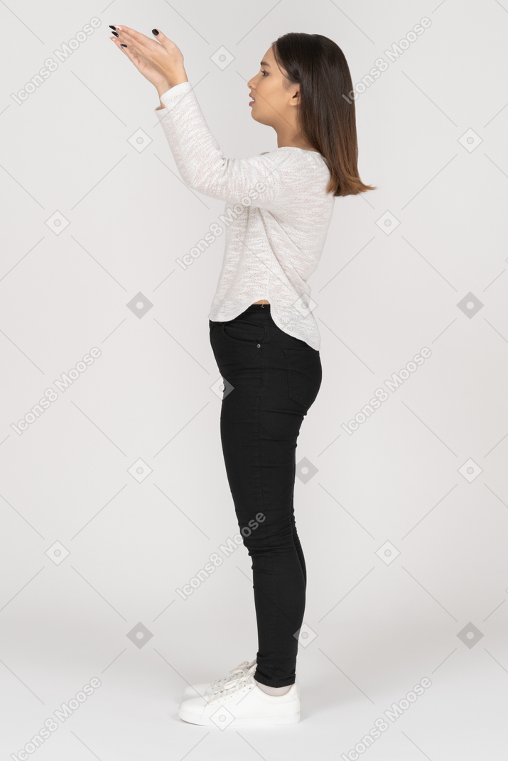 Side view of a questioning young indian female in casual clothes raising hands