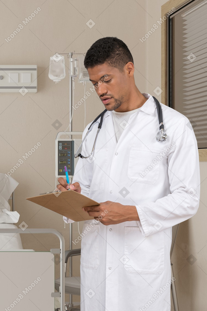Молодой мужской доктор что-то пишет на планшете
