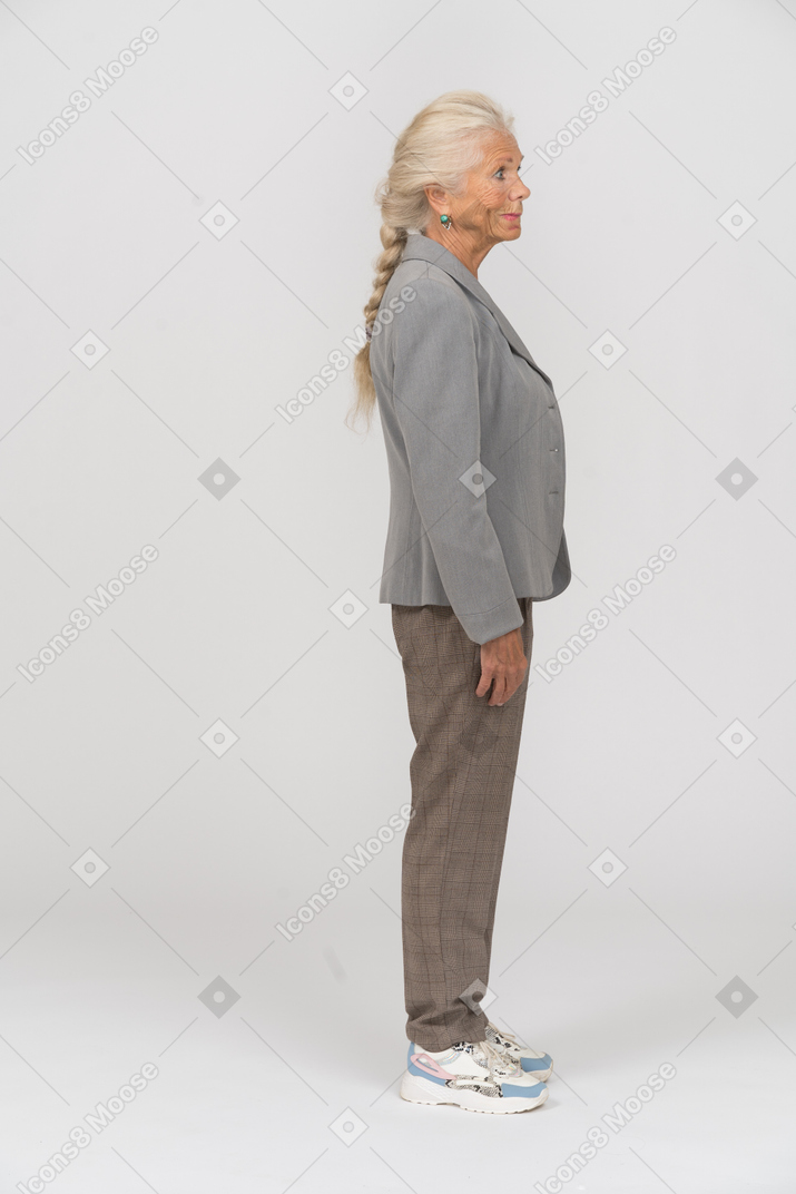 Vecchia donna in giacca grigia in piedi di profilo